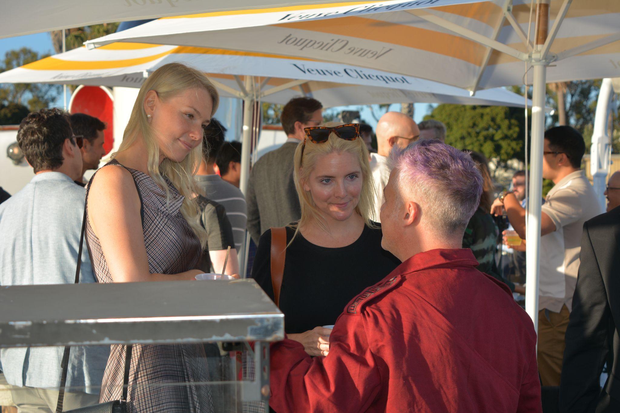 Guests talking beneath umbrellas on the yacht deck.